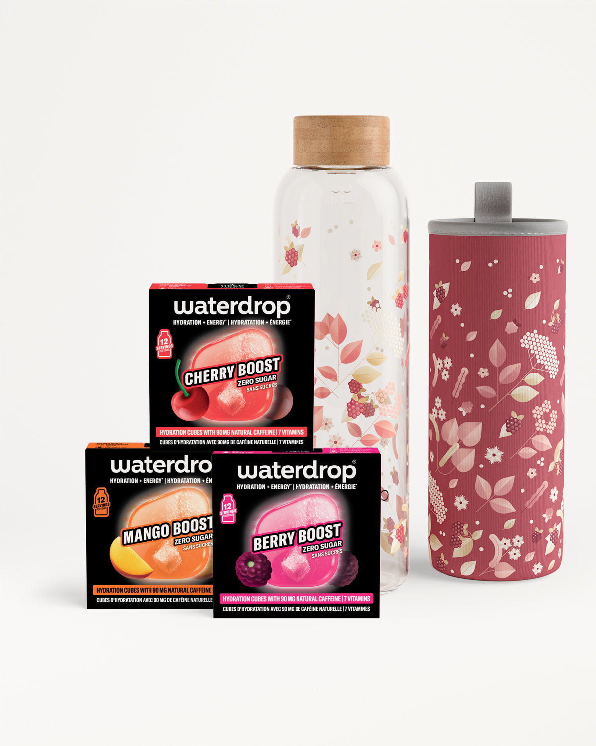 Assortiment de trois sachets Flavor Boost à côté d'une bouteille en verre transparente avec bouchon en bois et d'un grand gobelet rose à motif floral.