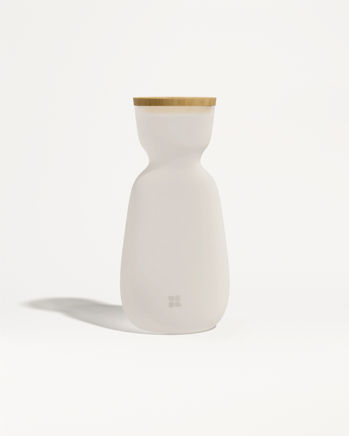 Bouteille en céramique blanche avec un couvercle en bois clair et un corps lisse et incurvé.
