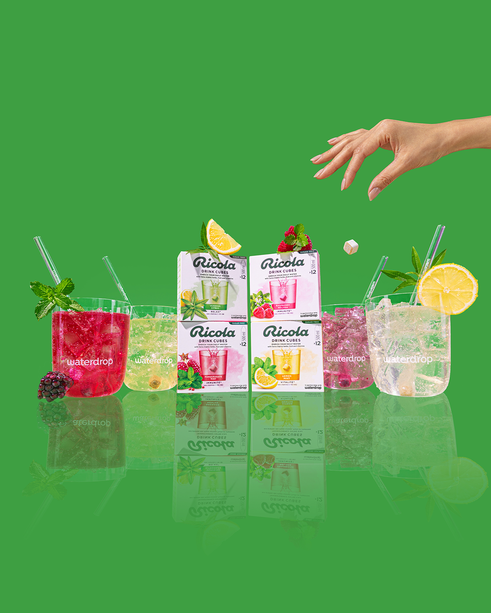 Ricola flavours in Glasses. A hand in the top right corner is dropping a drink cube into a glass.
