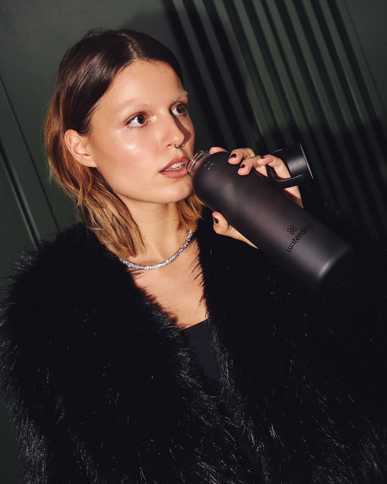 Woman sipping from Coffret Cadeau Verre Givré Soda bottle.