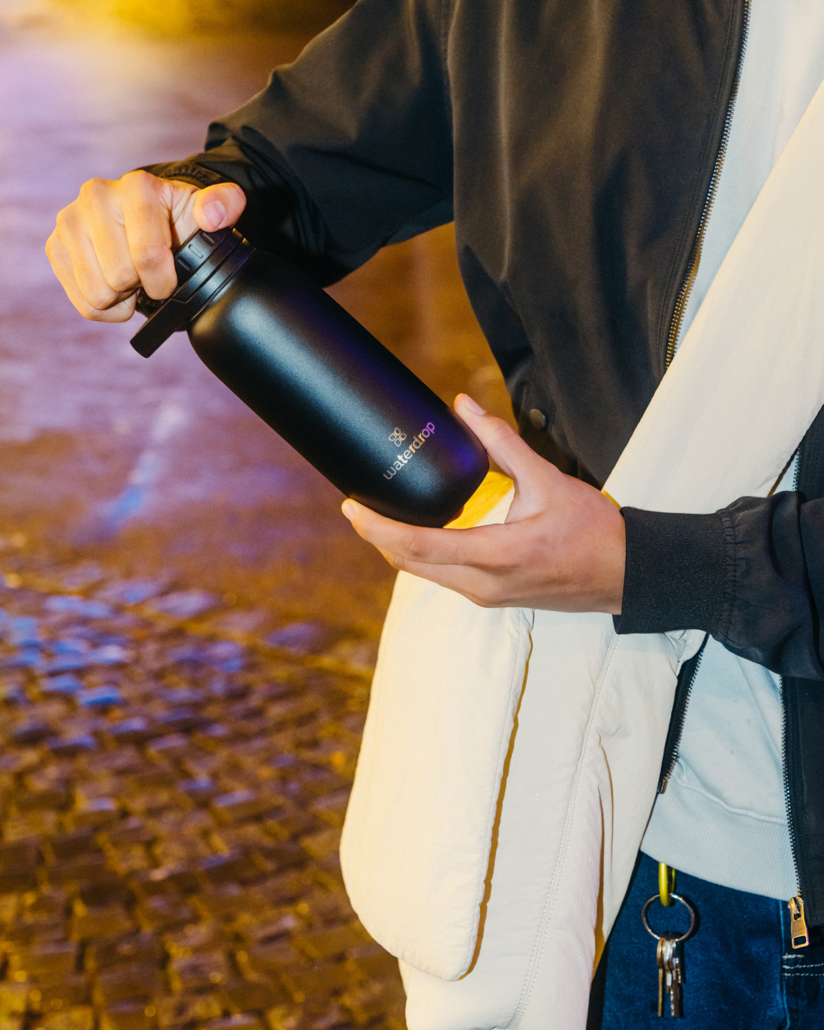 Person holding Gourde Sport Ultralight bottle, twisting lid.