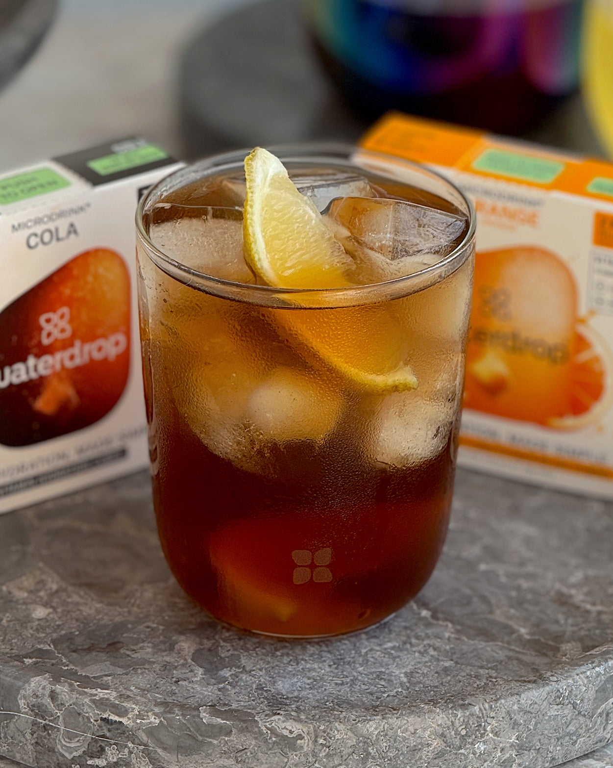 Coffret 3+1 Cola Orange drink in glass with lemon garnish.