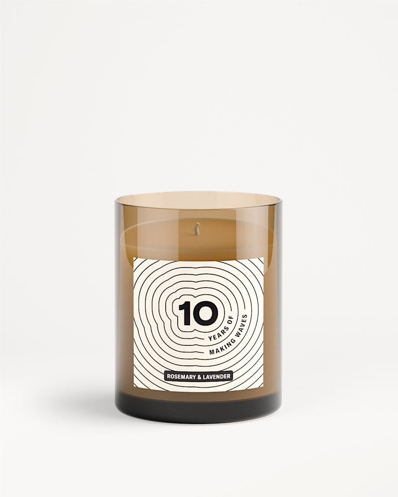 Bougie dans un bocal en verre brun avec étiquette blanche et motif de cercles concentriques.