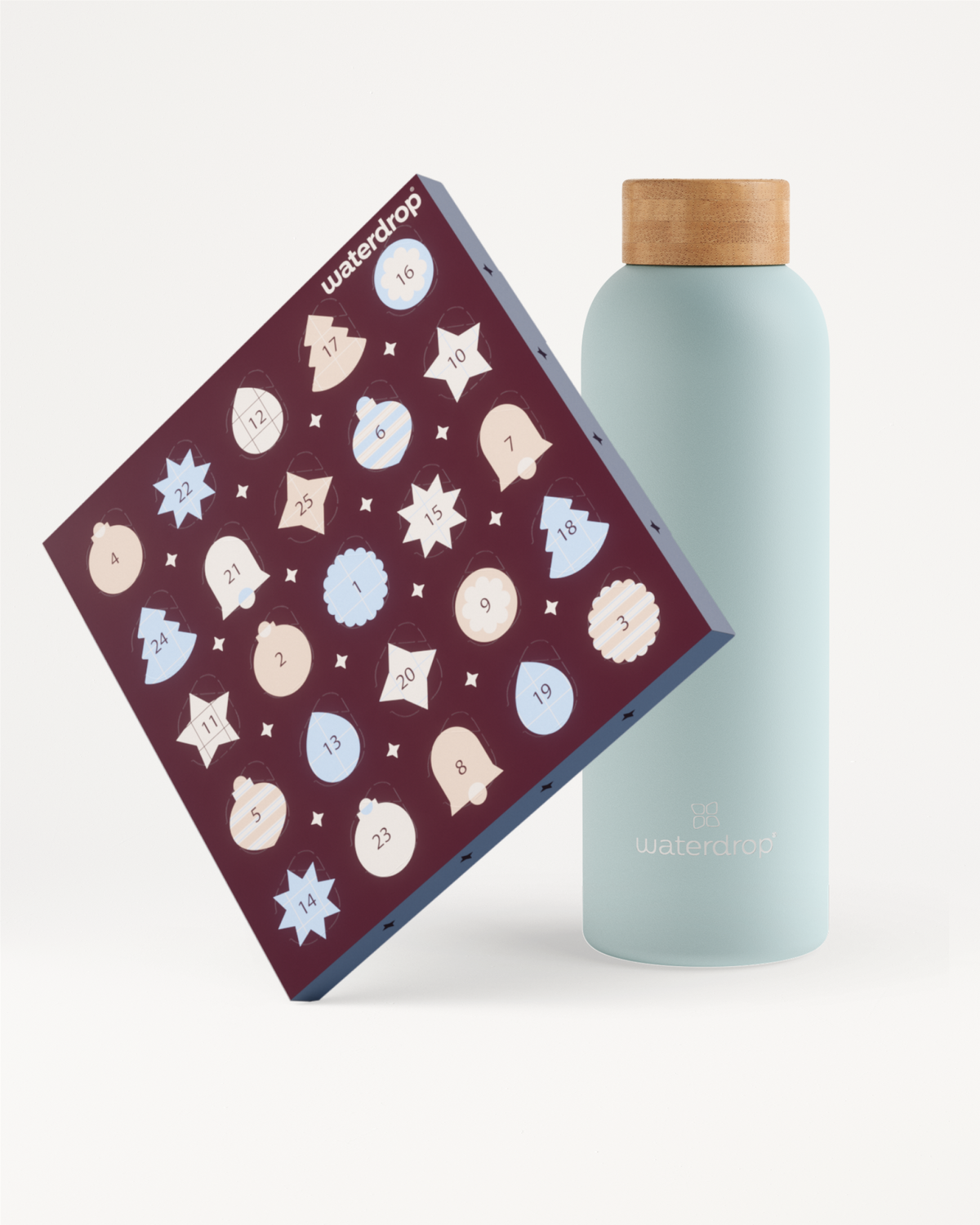Bouteille réutilisable bleu clair avec bouchon en bois à côté d’un calendrier de l’Avent violet décoré de flocons de neige blancs et bleus.