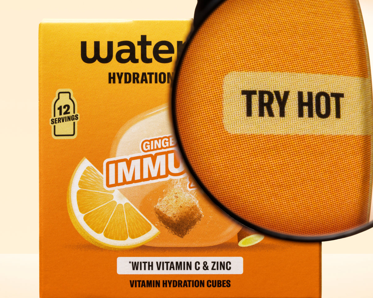 Boîte orange avec graphique de citron et une loupe superposée, cubes d'hydratation vitaminiques.
