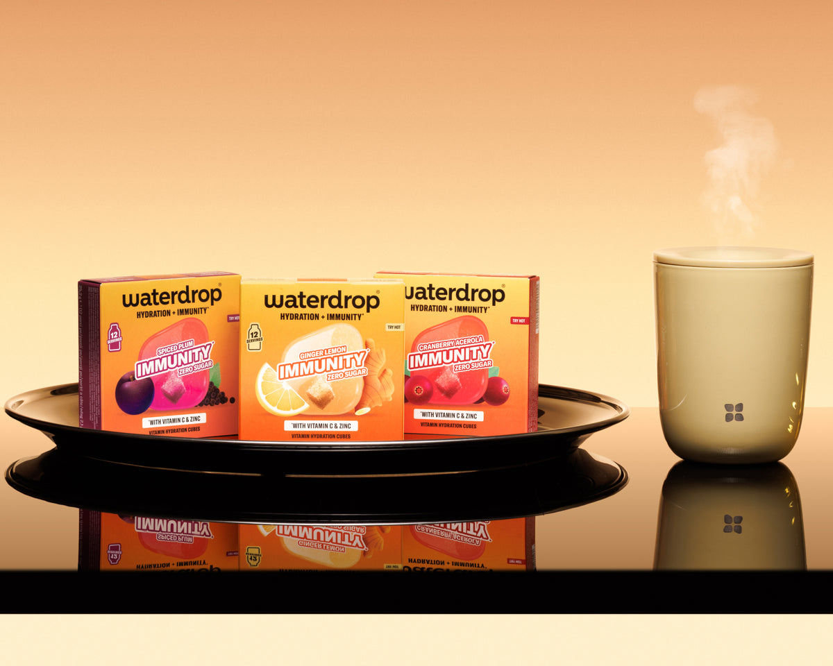 Trois boîtes orange sur un plateau noir, à côté d’un diffuseur blanc émettant de la vapeur, sur fond chaleureux.