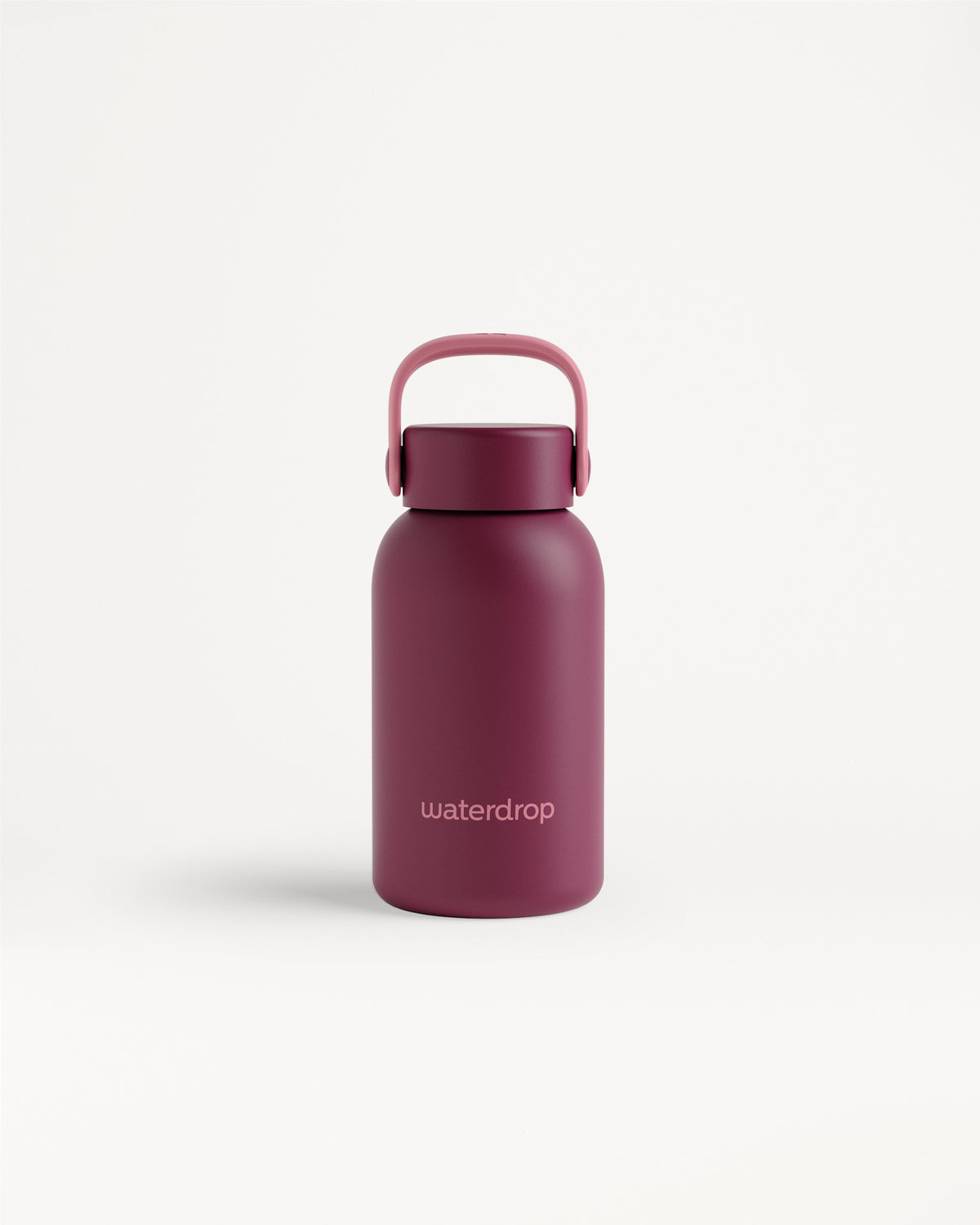 Bouteille d'eau réutilisable magenta avec une poignée incurvée sur fond blanc.